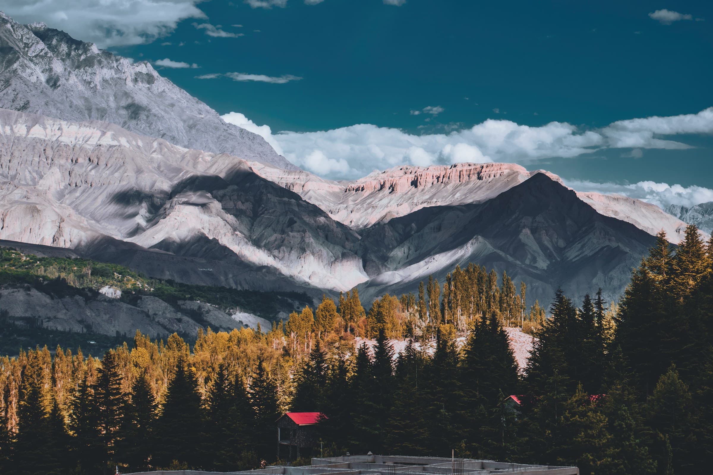 Mountain valley orchard with a red-roofed hut below the peaks
